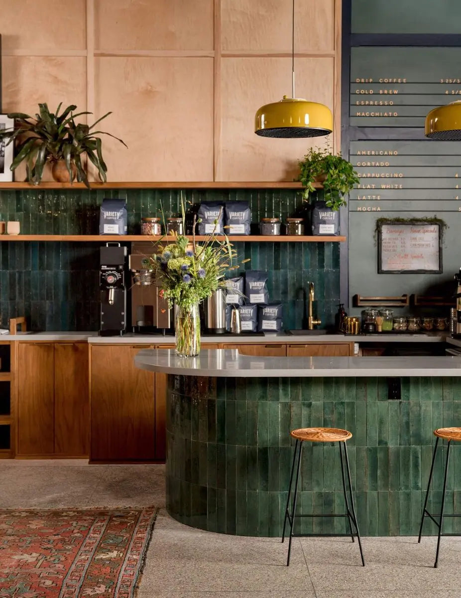 A deep green bar counter framed by hanging and potted greenery