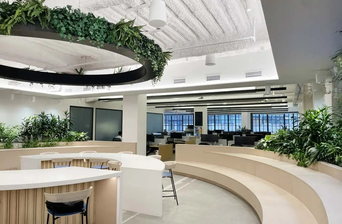 Curved white office counters surrounded by planted greenery and a suspended garden